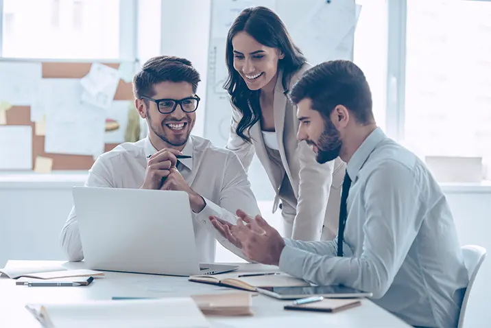 Team bespricht gemeinsam Inhalte am Laptop in einem modernen Büro